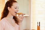 Side view of woman biting into slice of bread