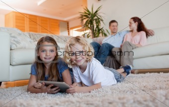 Brother and daughter using tablet on the carpet