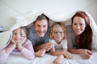 Happy family under bed cover
