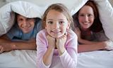 Girl under bed cover with parents