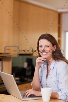 Smiling woman with laptop in the kitchen