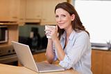 Woman drinking coffee while on laptop