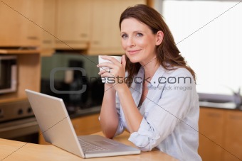 Woman drinking coffee while on laptop