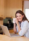 Woman with cup next to laptop