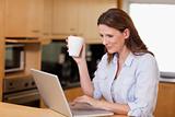 Woman drinking tea while on laptop