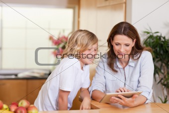 Woman and son using tablet in the kitchen