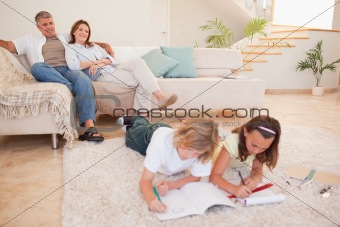 Children doing homework with parents behind them