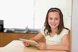 Smiling girl with tablet at kitchen table