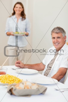 Man waiting for his wife to bring salad to the table