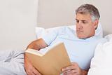 Mature man reading book in bed