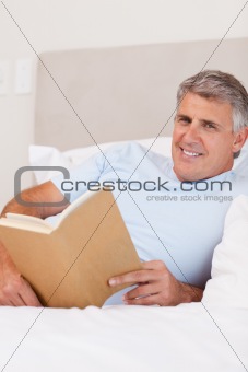 Smiling man reading in bed