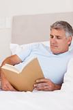 Man reading book in bed