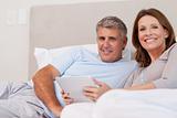 Couple with tablet in bed