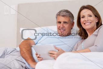 Couple with tablet in bed