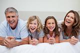 Laughing family lying on the bed