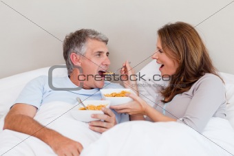 Mature couple eating cereals in bed