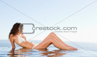 Woman laying on pool edge enjoying the sun