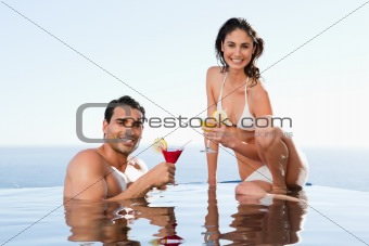 Cheerful couple having cocktails in the pool
