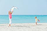 girl with brother on beach playing with a kite
