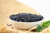 Bowl of black lentils  on white background