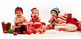 Four babies in xmas costumes playing among gifts