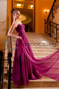  woman in a beautiful dress sloit on the stairs