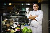 asian chef smiling at camera in restaurant kitchen