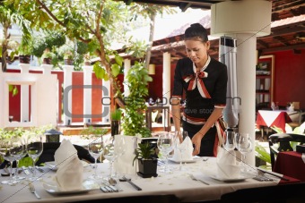 asian waitress setting table in restaurant