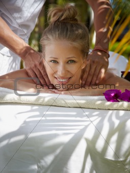 Happy young woman smiling during massage in spa