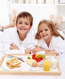Happy kids having breakfast in bed
