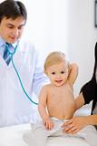 Portrait of happy baby being checked by pediatric doctor using a stethoscope 
