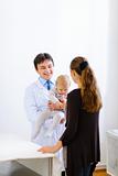 Pediatric doctor holding baby and talking with mother
