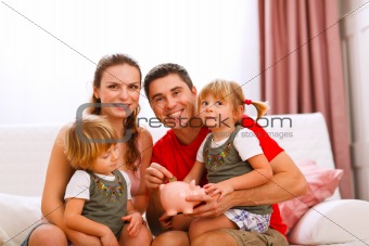 Family portrait where father putting coin to piggy bank 
