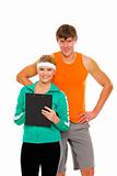 Portrait of young man and fit girl in sportswear with clipboard isolated on white
