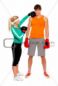 Slim girl in boxing gloves punching man isolated on white

