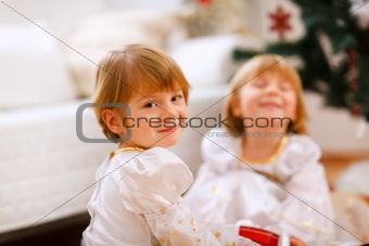 Portrait of happy girl playing with sister near Christmas tree

