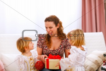 Happy mother holding gift of her twins daughters
