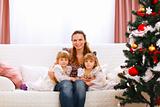 Portrait of mother with two twins daughters near Christmas tree
