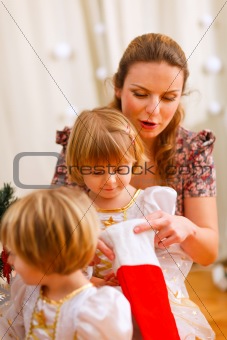Mother looking with twins daughters inside of Christmas socks
