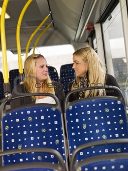 Two young women chatting on the bus