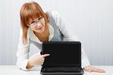 girl with glasses shows a finger on a laptop