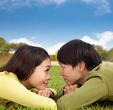 Happy asian couple lying on the grass with cloud background