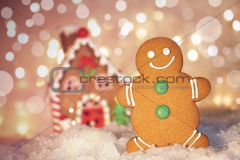 Gingerbread man cookie standing beside house 