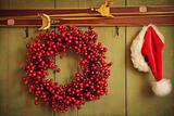  Red wreath with Santa hat hanging on rustic wall