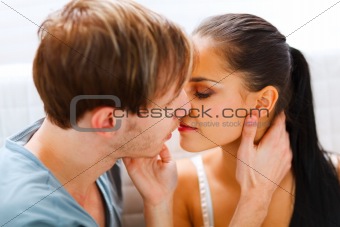 Romantic young couple sitting on divan and kissing
