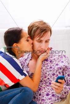 Girl trying to distract her busy boyfriend from mobile phone 
