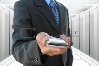 businessman hand holding mobile phone in the communication and internet network server room
