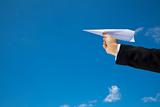 hand of Businessman letting an airplane made of paper fly over blue sky