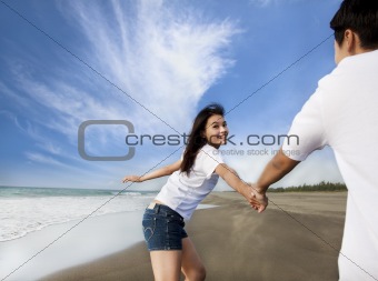happy asian couple running on the beach