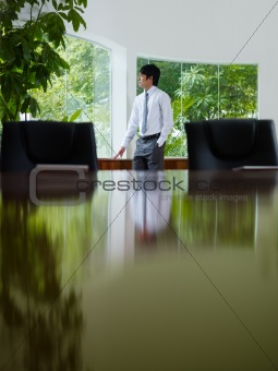 businessman contemplating out of window in meeting room